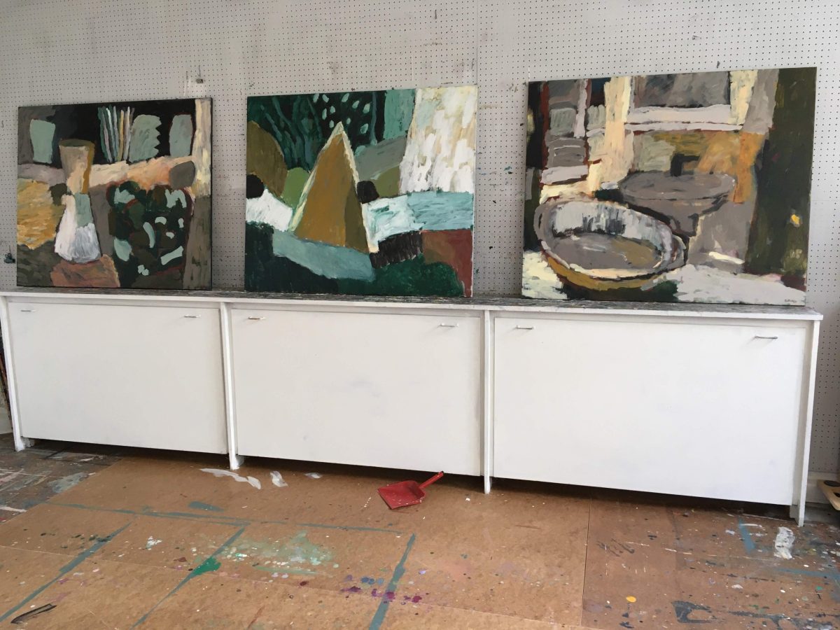 Hylde med tre malerier i atelier
